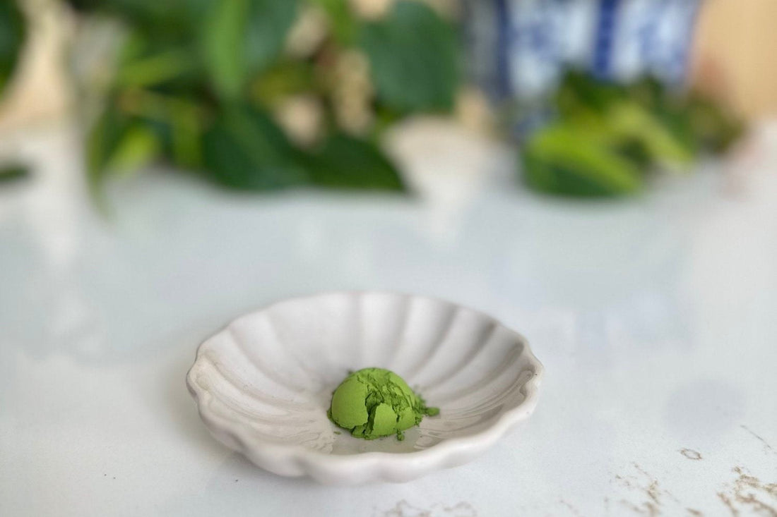 Vibrant green ceremonial matcha powder on a white fluted dish, showing the bright color of high-quality matcha