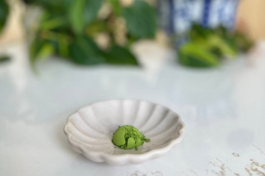 Vibrant green ceremonial matcha powder on a white fluted dish, showing the bright color of high-quality matcha